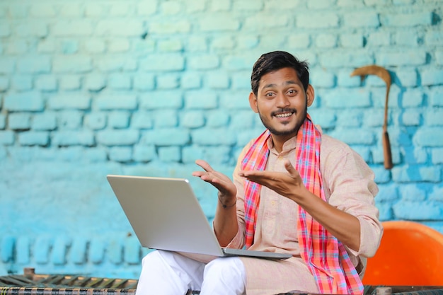 Conceito de tecnologia: fazendeiro indiano usando laptop em casa.