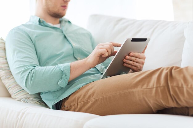 conceito de tecnologia, lazer, estilo de vida e ensino à distância - close-up do homem trabalhando com computador tablet pc sentado ou deitado no sofá em casa