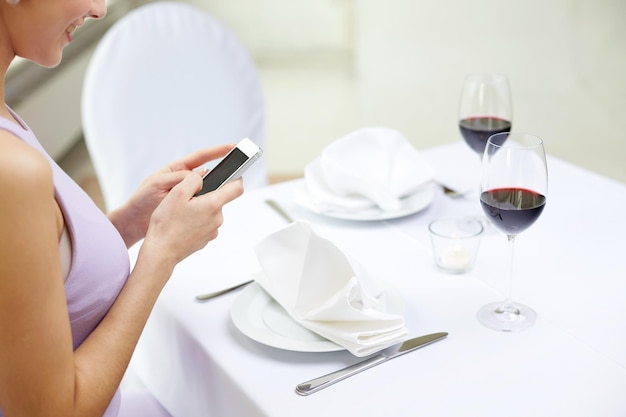 conceito de tecnologia, pessoas, comida e jantar - close-up de mulher com smartphone no restaurante