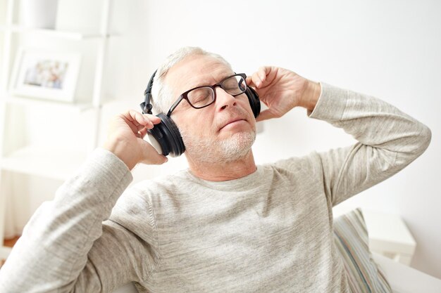 conceito de tecnologia, pessoas e estilo de vida - homem sênior feliz em fones de ouvido ouvindo música em casa