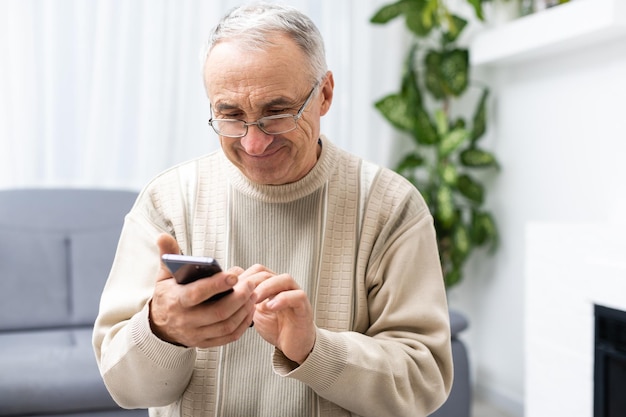 Foto conceito de tecnologia, pessoas, estilo de vida e comunicação - homem sênior feliz discando o número de telefone e enviando mensagens de texto no smartphone em casa.