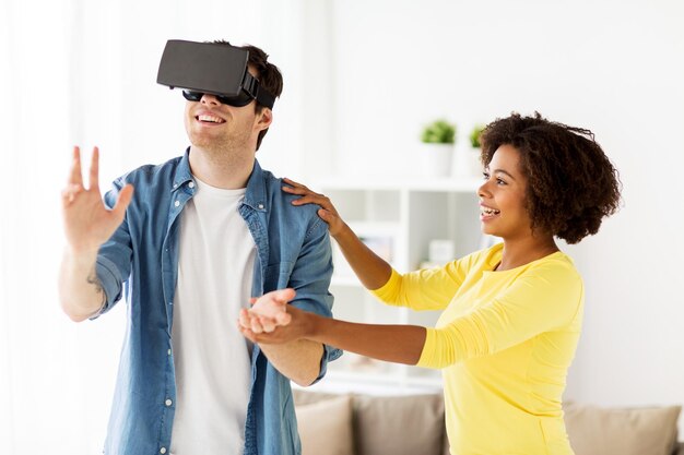 Foto conceito de tecnologia, realidade aumentada, jogos, entretenimento e pessoas - casal feliz com fone de ouvido virtual ou óculos 3d jogando em casa