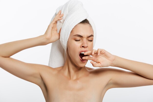 Foto conceito de tédio de cansaço mulher sonolenta colocando a mão na boca bocejando enquanto segura a toalha na cabeça