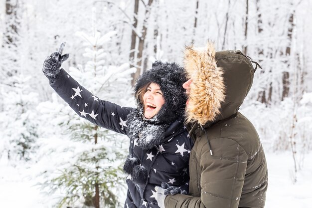 Conceito de temporada e relacionamento - casal engraçado tirando uma selfie no inverno