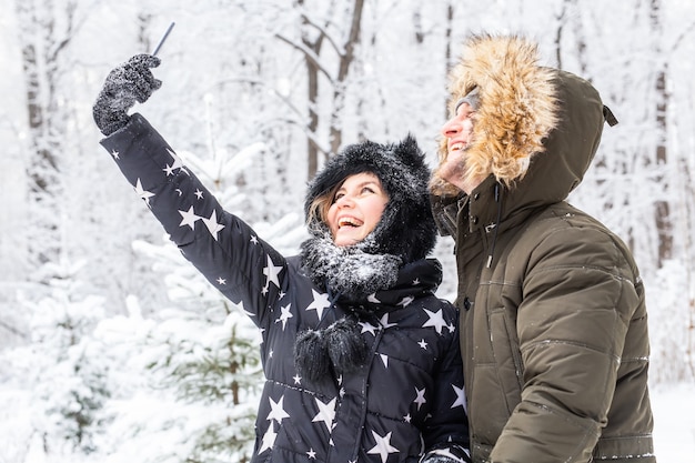 Conceito de temporada e relacionamento - casal engraçado tirando uma selfie no inverno