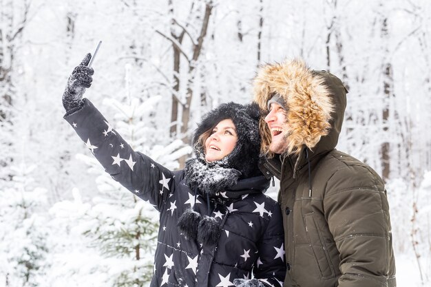 Conceito de temporada e relacionamento - casal engraçado tirando uma selfie no inverno