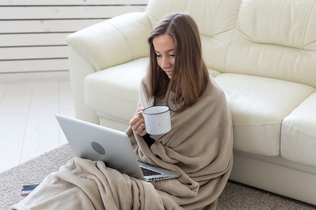 Conceito de trabalho, acolhedor, de pessoas - jovem trabalhando em casa em um xadrez, bebendo chá e conversando