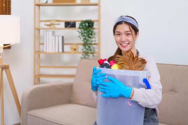 Conceito de trabalho doméstico a empregada doméstica usa luva e segura material de limpeza para preparar a limpeza da casa