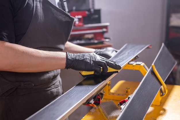 Conceito de trabalho e reparo - as mãos de um homem consertando o esqui esfregando uma parafina