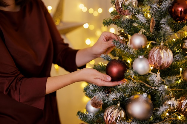 Conceito de tradição de Natal - close-up de uma linda mulher decorando a árvore de Natal