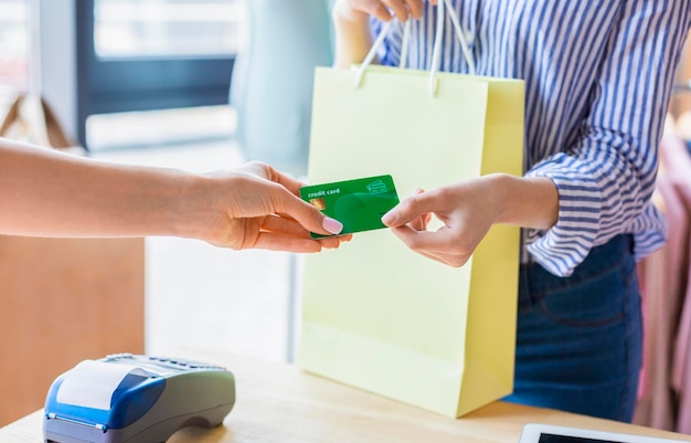 Conceito de transação sem dinheiro. Mulher caucasiana pagando com cartão de crédito para compra no showroom de roupas