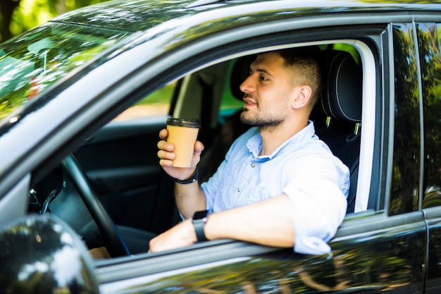 Conceito de transporte e veículo Jovem bebendo café enquanto dirige o carro