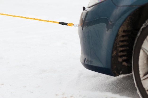 Conceito de transporte, inverno e veículo - closeup de carro rebocado com corda de reboque