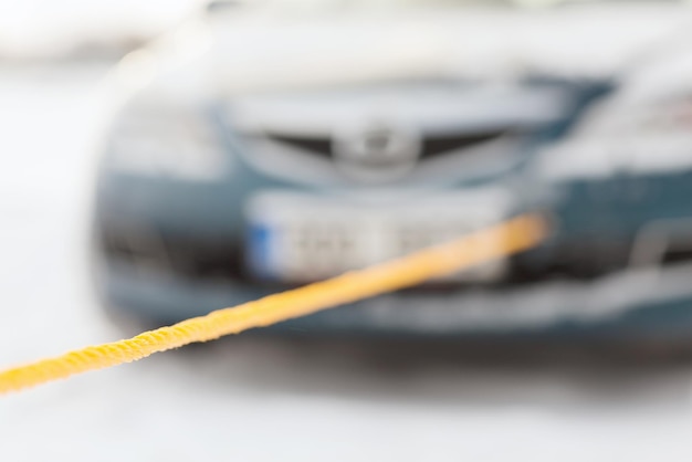 conceito de transporte, inverno e veículo - closeup de carro rebocado com corda de reboque