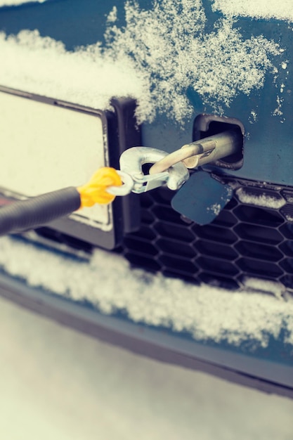 Conceito de transporte, inverno e veículo - closeup de carro rebocado com corda de reboque