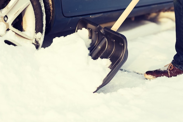 conceito de transporte, inverno e veículo - closeup de homem cavando preso no carro de neve