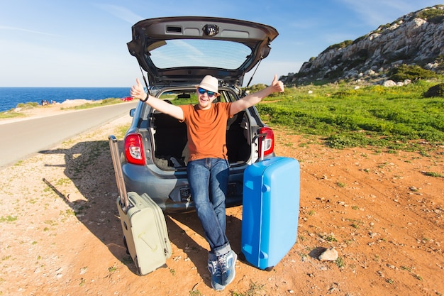 Conceito de transporte, lazer, road trip e pessoas. homem feliz, aproveitando a viagem e as férias de verão.