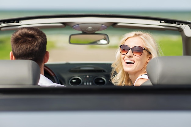 conceito de transporte, viagem, lazer, casal e pessoas - homem e mulher felizes dirigindo em carro conversível ao ar livre