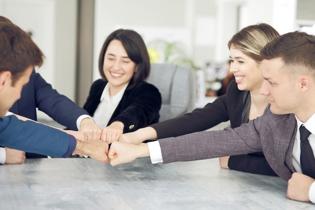 Foto conceito de unidade e trabalho em equipe de jovens empresários, juntando as mãos.