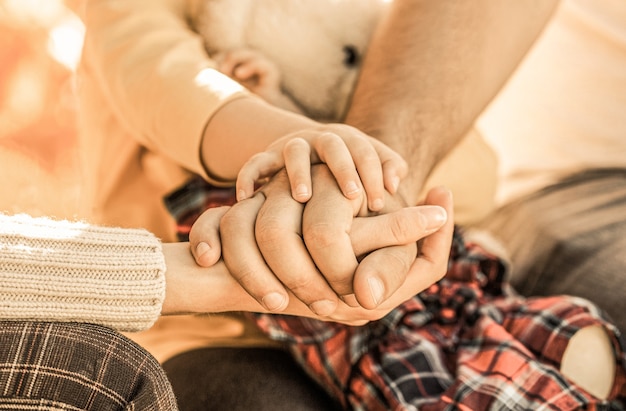 Conceito de unidade, suporte, proteção, felicidade. Closeup de mão de criança em pais. Mãos de pai, mãe, mantenham a mão do bebezinho.