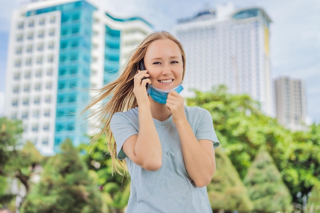 Foto conceito de uso impróprio de máscara mulher que usava máscara erroneamente tirou a máscara enquanto falava ao telefone