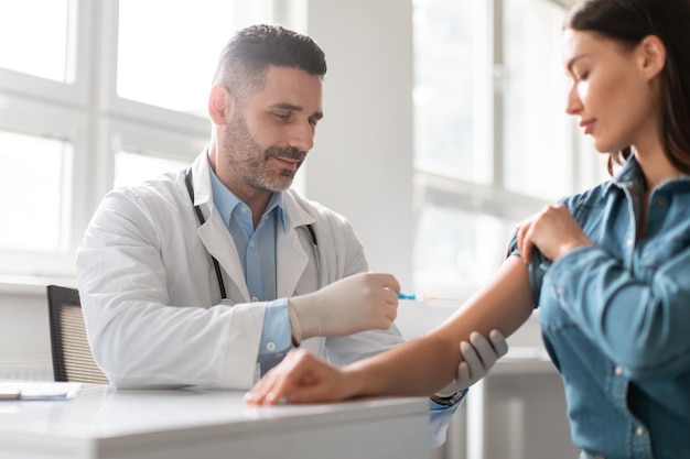 Conceito de vacinação e imunização senhora grávida recebendo vacina no hospital sentado na clínica