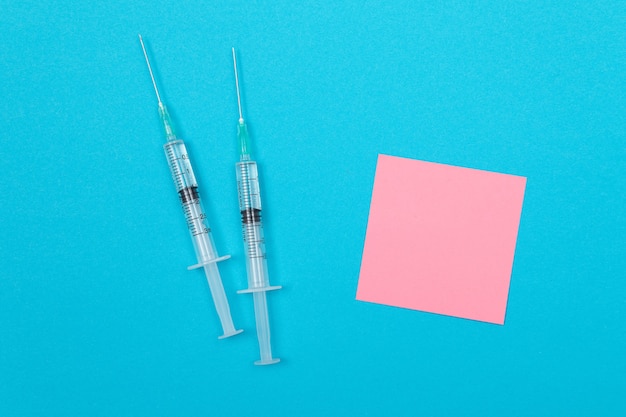 Foto conceito de vacinação ou revacinação duas seringas médicas na mesa azul