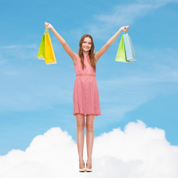 conceito de varejo e venda - mulher sorridente de vestido e salto alto com muitas sacolas de compras