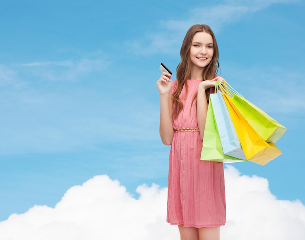 conceito de varejo e venda - mulher sorridente no vestido com muitas sacolas de compras e cartão de crédito