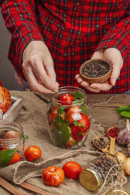 Conceito de vegetais de estação preservada Colheita de tomate, pimentão, cebola e alho As mãos da mulher preparam ingredientes para o processo de cozimento de alimentos enlatados Receitas saudáveis, cozinha caseira, espaço de cópia