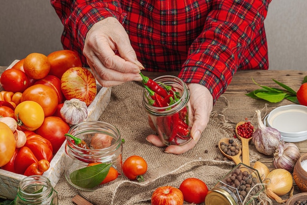 Conceito de vegetais de estação preservada Colheita de tomate, pimentão, cebola e alho As mãos da mulher preparam ingredientes para o processo de cozimento de alimentos enlatados Receitas saudáveis, cozinha caseira, espaço de cópia