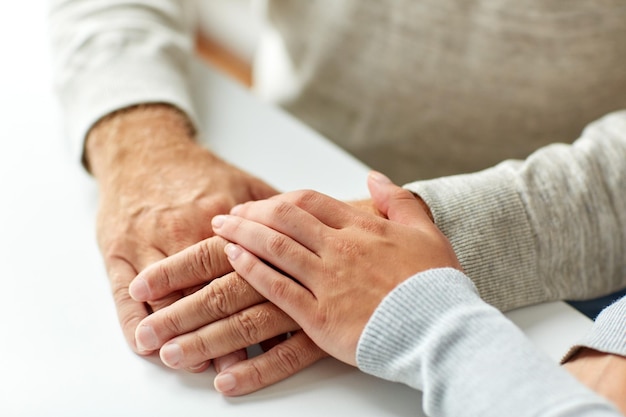 Foto conceito de velhice, apoio, caridade, cuidado e pessoas - close-up de um homem idoso e uma jovem de mãos dadas