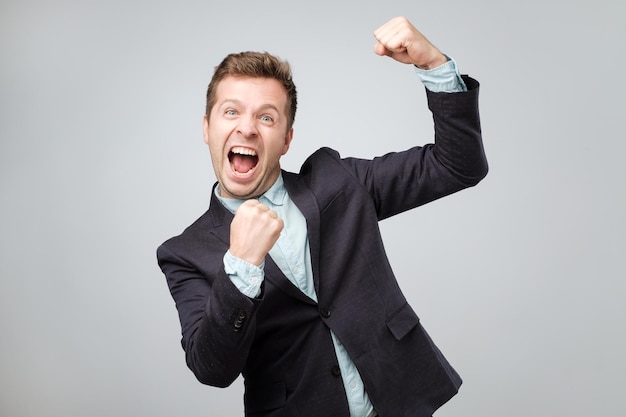 Conceito de vencedor sortudo O homem caucasiano emocional de terno é feliz e alegre porque ganhou muito dinheiro