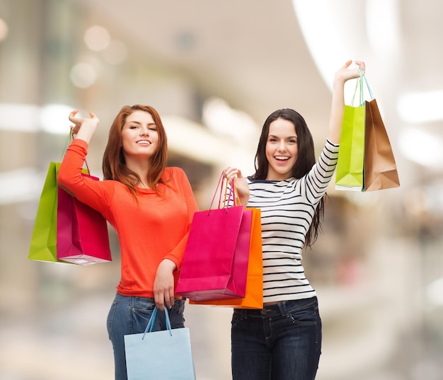 conceito de venda, amizade e pessoas - duas adolescentes sorridentes com sacolas de compras sobre fundo de shopping
