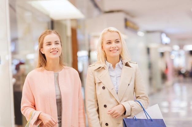 conceito de venda, consumismo e pessoas - mulheres jovens felizes com sacolas de compras no shopping