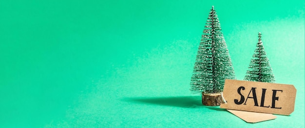 Conceito de venda de Natal em fundo turquesa. Etiqueta decorativa da árvore e do papel do abeto. Símbolo tradicional do ano novo. Uma luz forte, sombra escura na moda. Camada plana, maquete, modelo, formato de banner