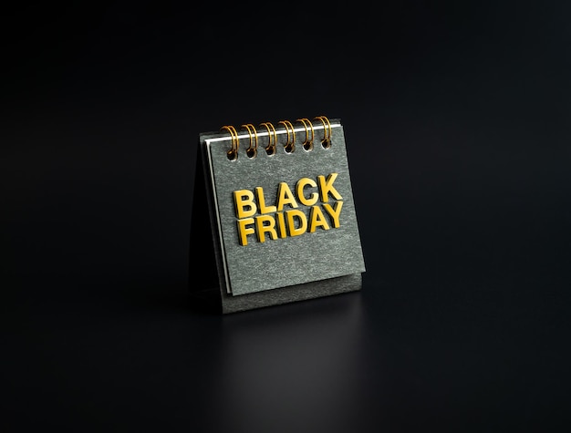 Conceito de venda de sexta-feira negra BLACK FRIDAY texto dourado basrelief na pequena capa de calendário de mesa espiral preta em pé no fundo escuro minimalista cartaz de cartão de convite e banner
