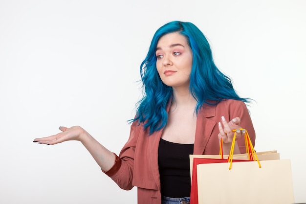 Conceito de venda, shopaholic e consumidor - linda garota com cabelo azul em pé com sacolas de compras