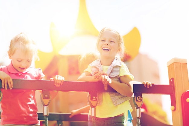 conceito de verão, infância, lazer, amizade e pessoas - meninas felizes rindo no parque infantil escalada