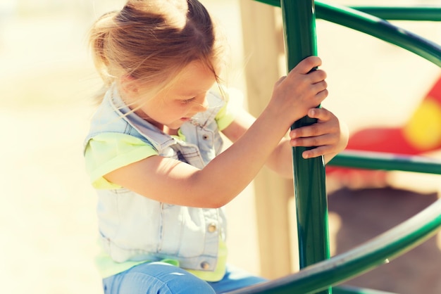 conceito de verão, infância, lazer e pessoas - menina feliz no quadro de escalada do parque infantil