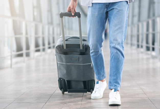 Conceito de viagem aérea homem caminhando com bagagem no corredor do aeroporto