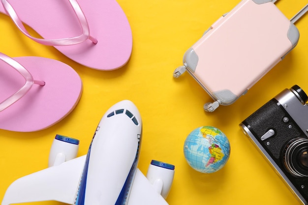 Conceito de viagem avião de passageiros de brinquedo e acessórios de viagem em fundo amarelo vista superior configuração plana