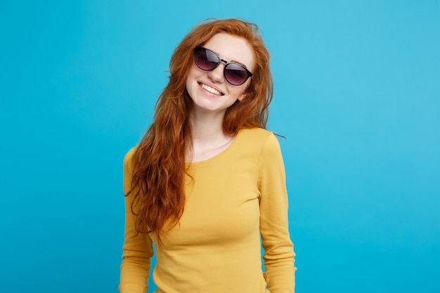 Conceito de viagem - close up retrato jovem e bonito atraente gengibre menina cabelo vermelho com sorvete na moda sorrindo. fundo pastel azul. copie o espaço.