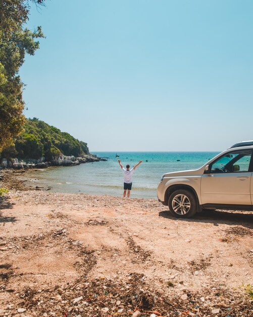 Foto conceito de viagem de carro homem na praia de verão olhando para a liberdade do mar