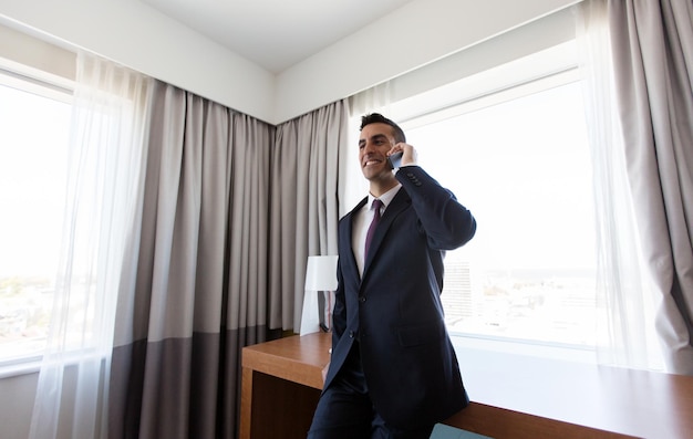 Foto conceito de viagem de negócios, pessoas e comunicação - empresário ligando para smartphone no quarto de hotel