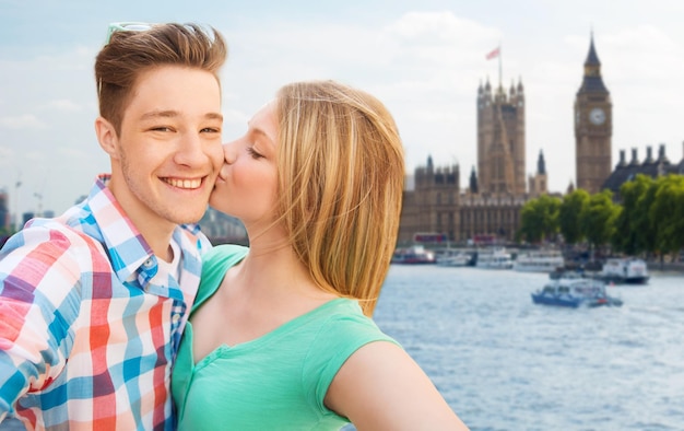 conceito de viagem, férias, tecnologia e amizade - casal feliz tomando selfie sobre casas do parlamento e rio tâmisa no fundo de londres