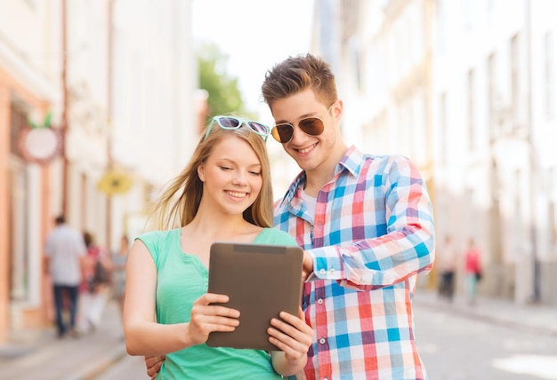 conceito de viagem, férias, tecnologia e amizade - casal sorridente com computador tablet pc na cidade