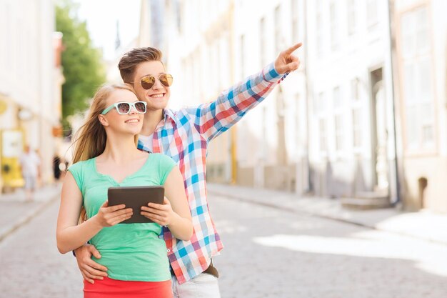 conceito de viagem, férias, tecnologia e amizade - casal sorridente com computador tablet pc na cidade