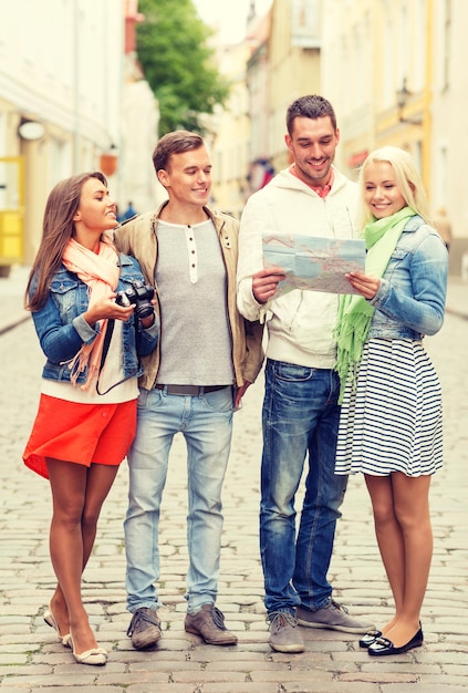 conceito de viagem, férias, tecnologia e amizade - grupo de amigos sorridentes com mapa e fotocâmera explorando a cidade