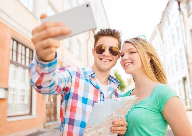 conceito de viagens, férias, tecnologia e amizade - casal sorridente com smartphone na cidade